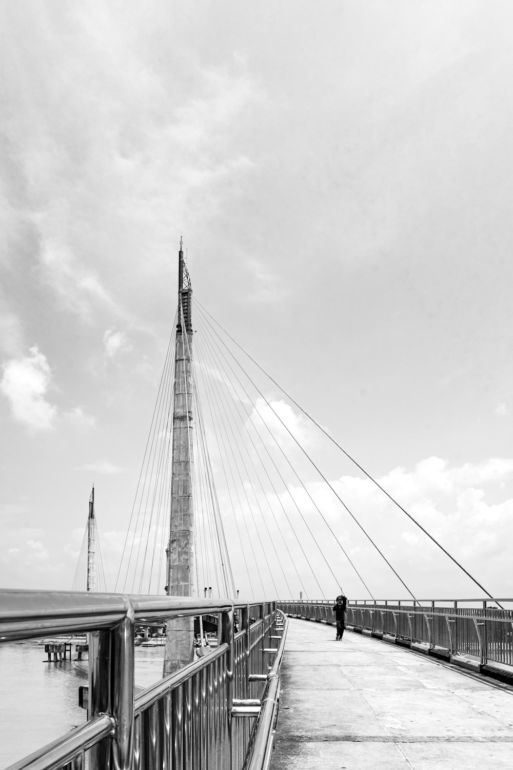 a black and white photo of a person walking on a bridge