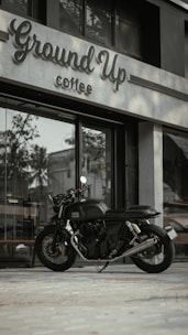 A sleek mobile coffee motorcycle parked in an industrial park setting, with a barista serving a fresh latte.