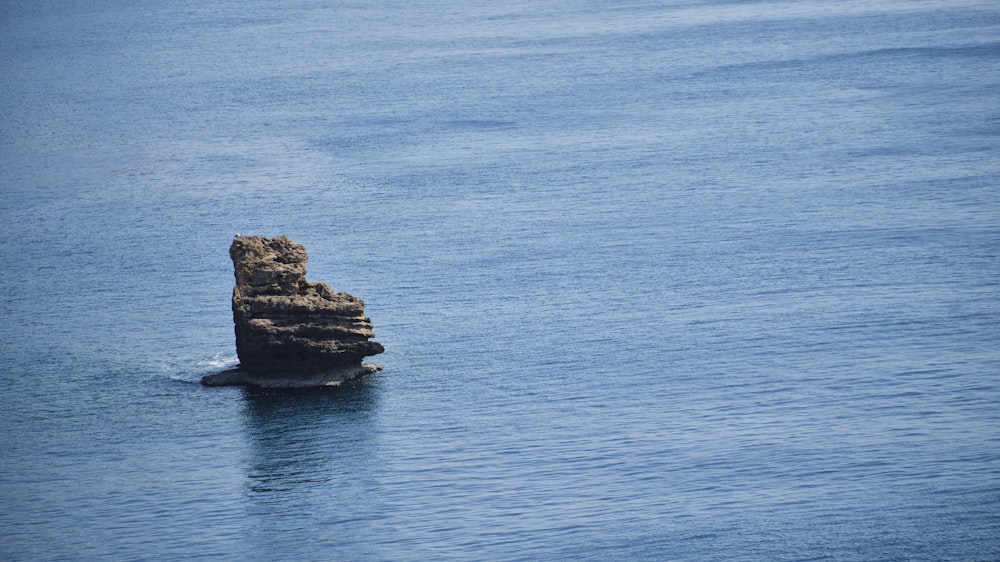 a large rock sticking out of the middle of a body of water