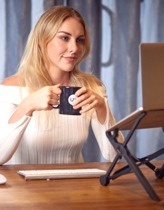 a woman sitting at a table with a laptop and a cup of coffee