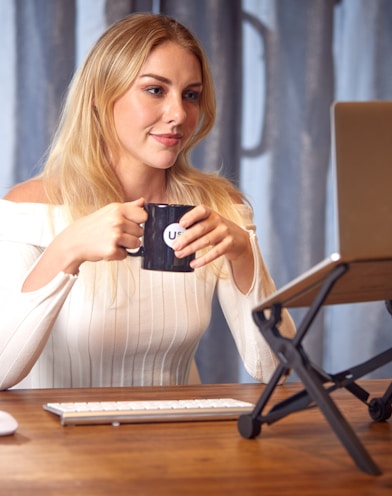 a woman sitting at a table with a laptop and a cup of coffee