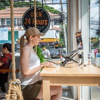 a woman sitting at a table with a plant in front of her