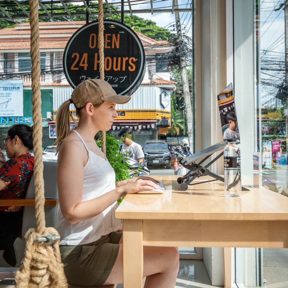 a woman sitting at a table with a plant in front of her