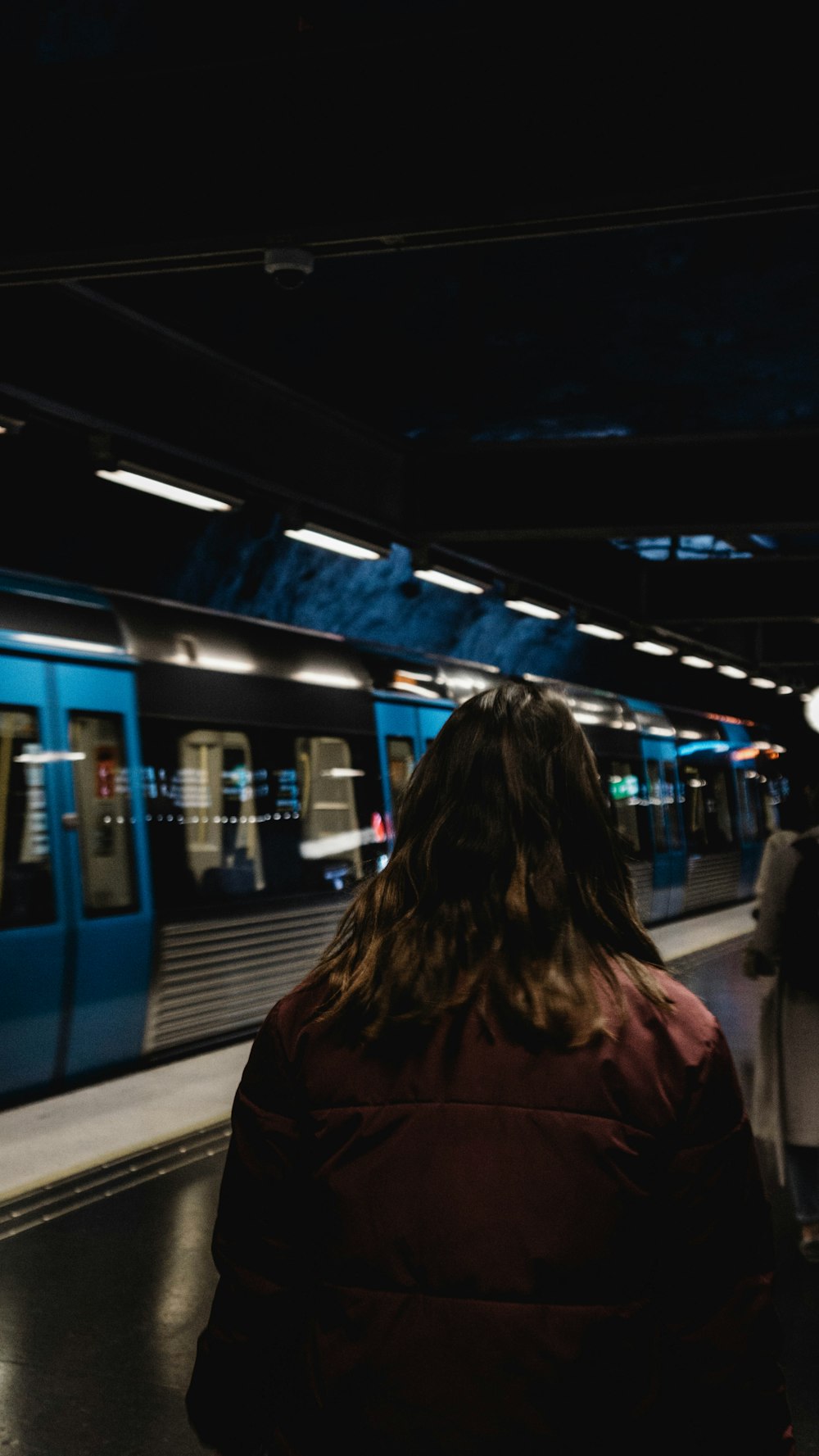 a woman is waiting for a train at a train station