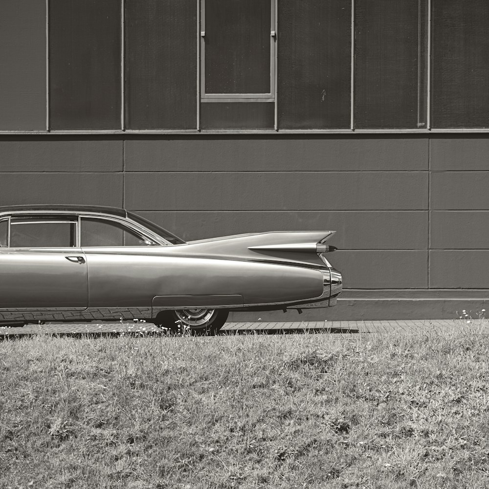 a black and white photo of a car parked in front of a building