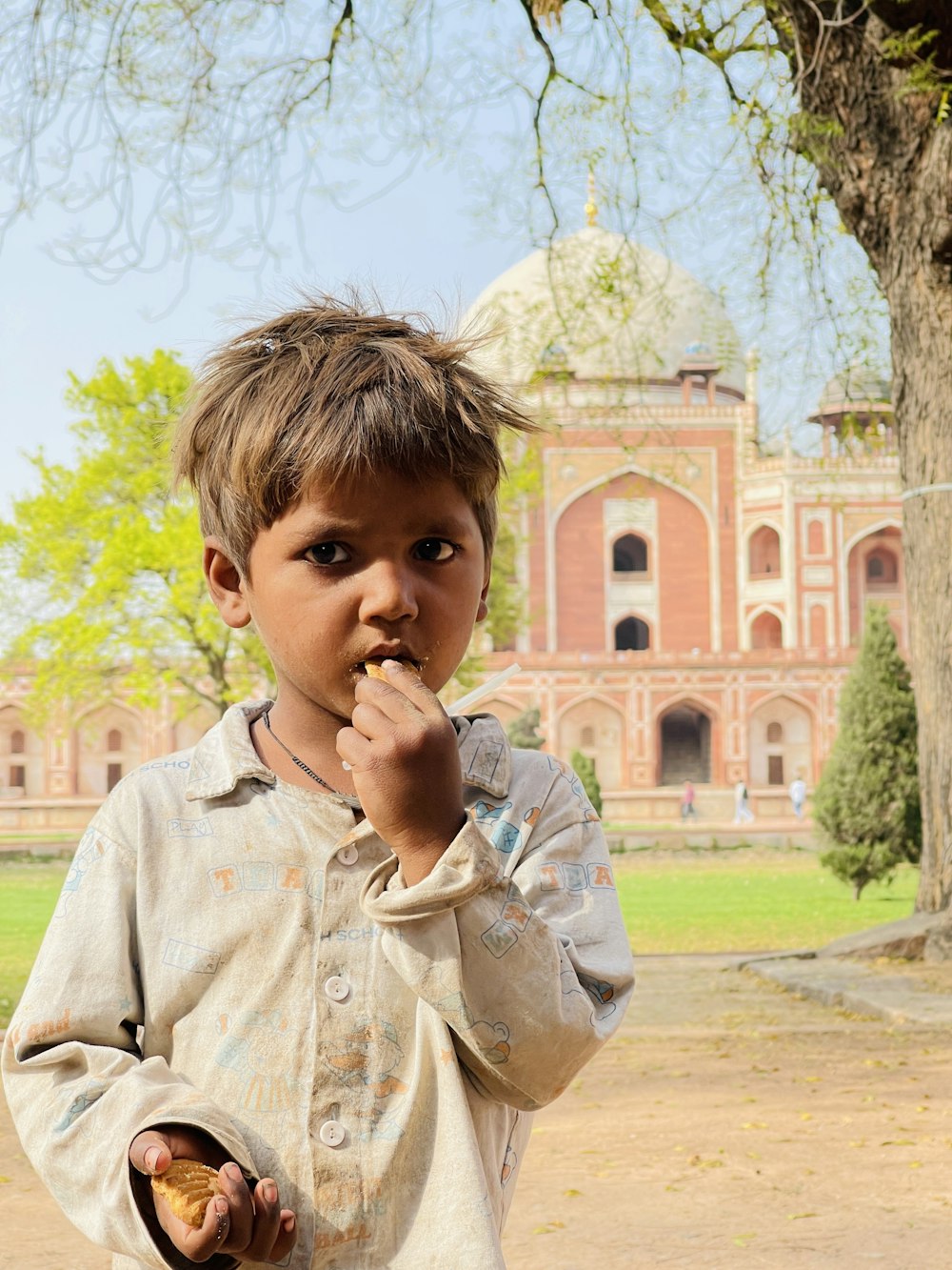 a young boy eating food in front of a building