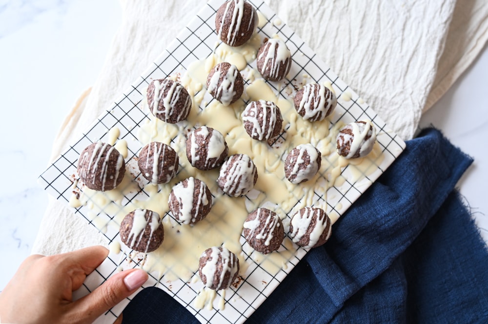 a person holding a tray of chocolate covered cookies