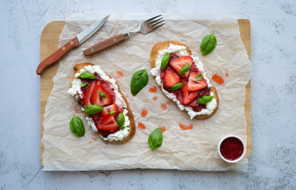 two pieces of bread topped with strawberries and cheese