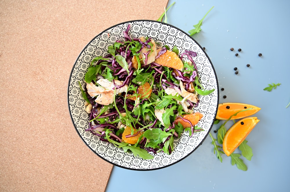 a salad with oranges and greens in a bowl