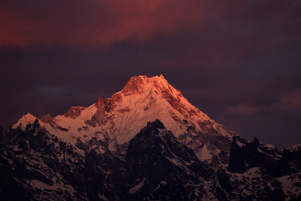 a snow covered mountain under a cloudy sky