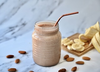 a glass jar filled with a smoothie next to sliced bananas