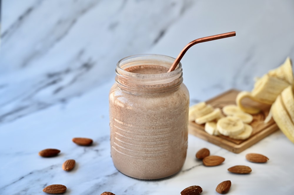 a glass jar filled with a smoothie next to sliced bananas