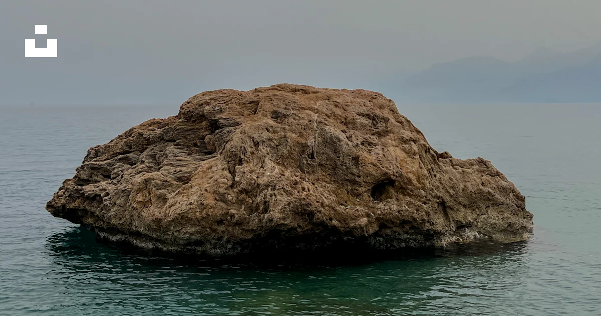 Gran Roca Foto Una gran roca sentada en medio de un cuerpo de agua – Imagen Gris ...