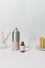 a white table topped with a bottle of liquid and a brush