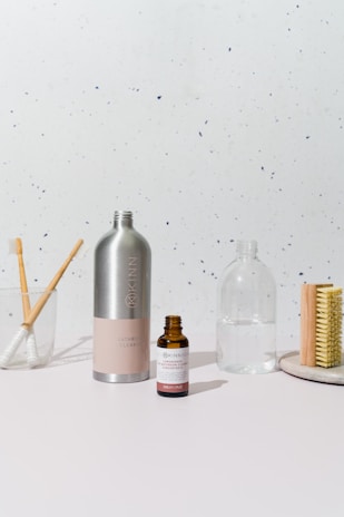 a white table topped with a bottle of liquid and a brush