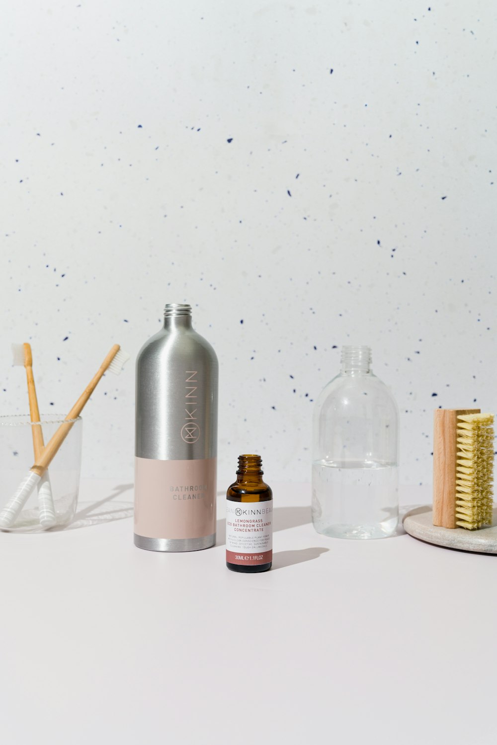 a white table topped with a bottle of liquid and a brush