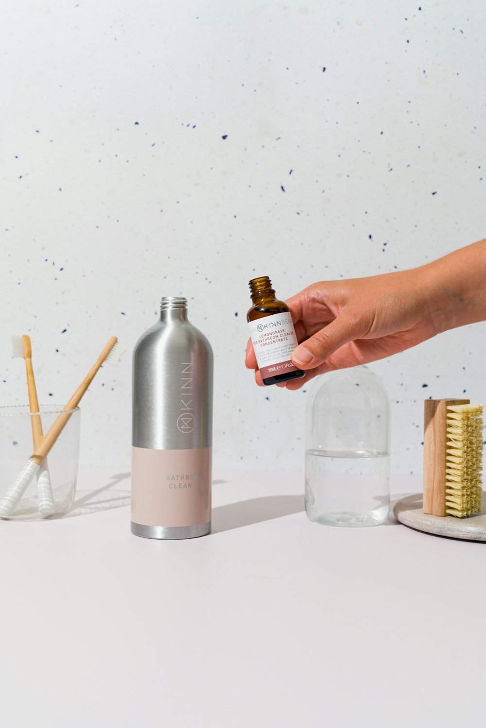 a person holding a bottle of essential oil next to a brush