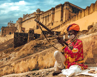 a man sitting on a rock with a stick in his hand
