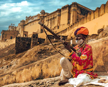 a man sitting on a rock with a stick in his hand