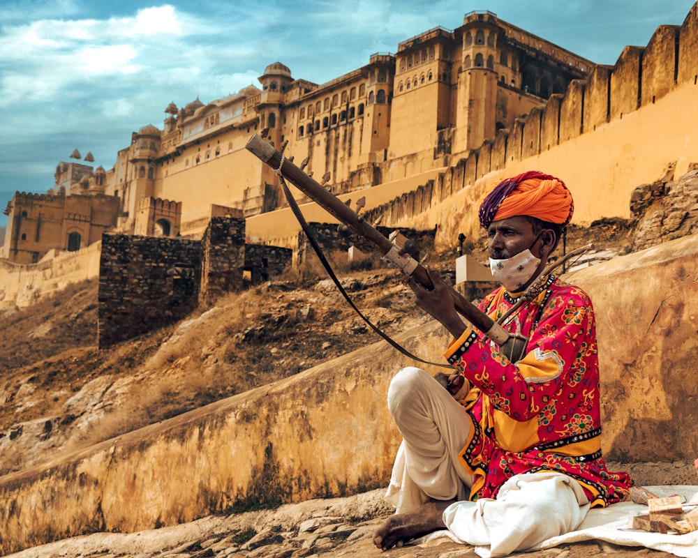 a man sitting on a rock with a stick in his hand