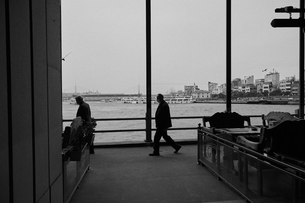 a man walking down a walkway next to a body of water