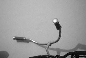 A close-up of the handlebars of a bicycle with rubber grips. The composition is simple, showing part of the handlebar against a plain background.