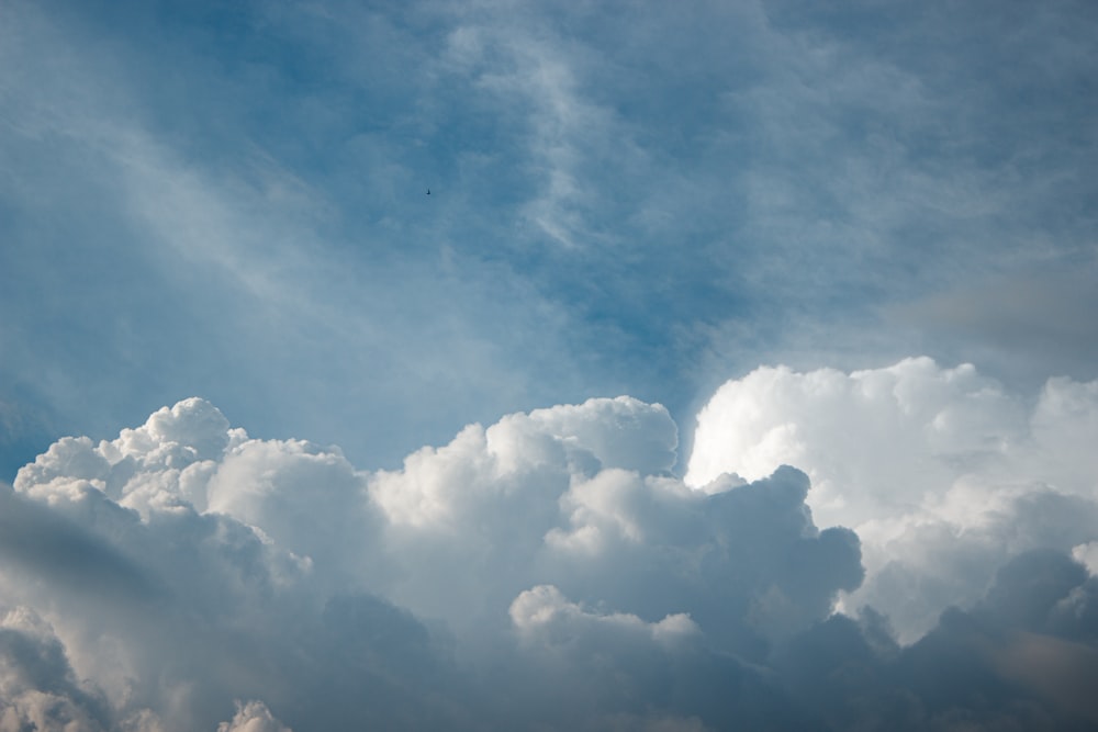 a plane flying through a cloudy blue sky