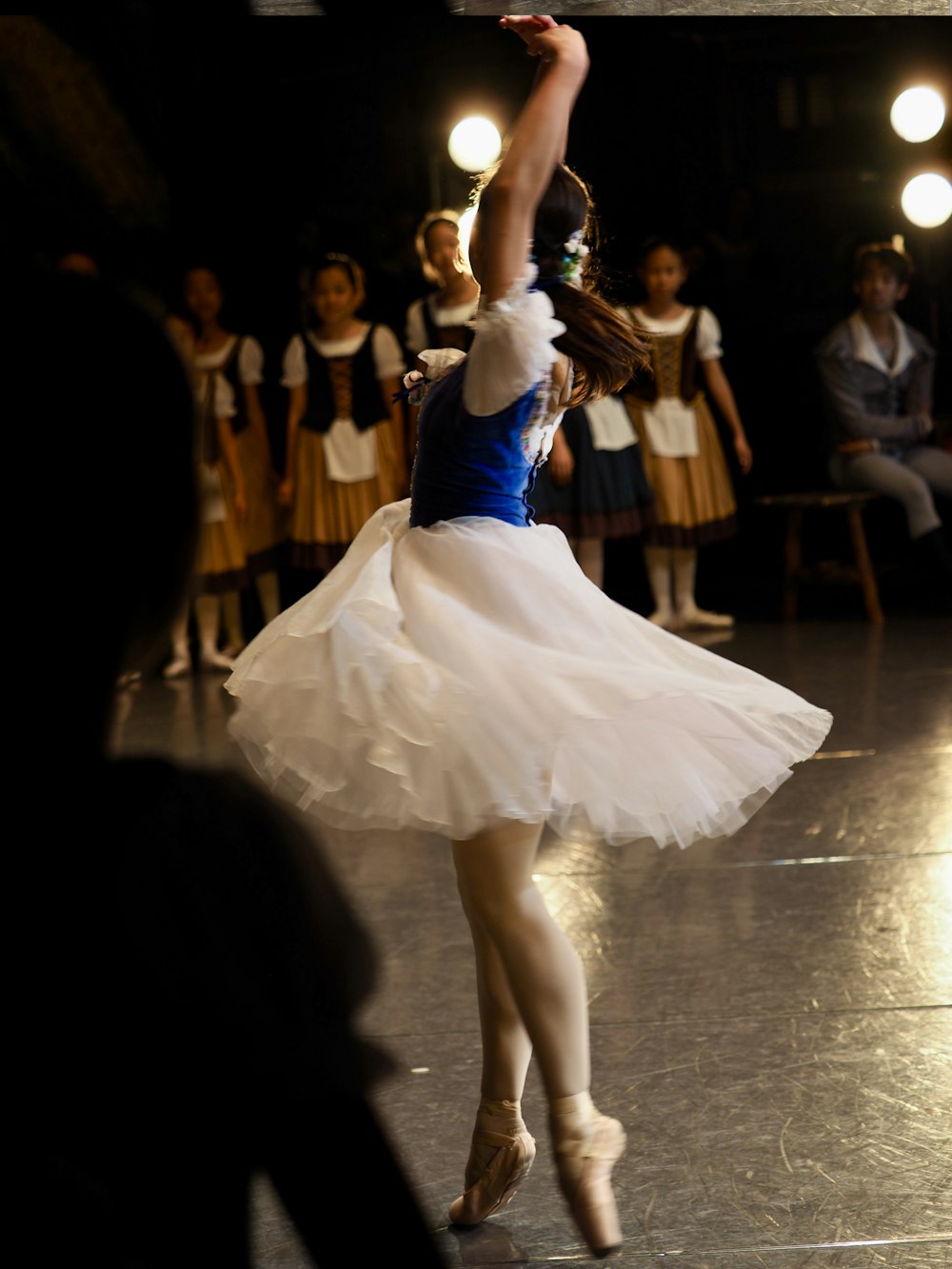 a young girl in a white tutu dancing on a stage