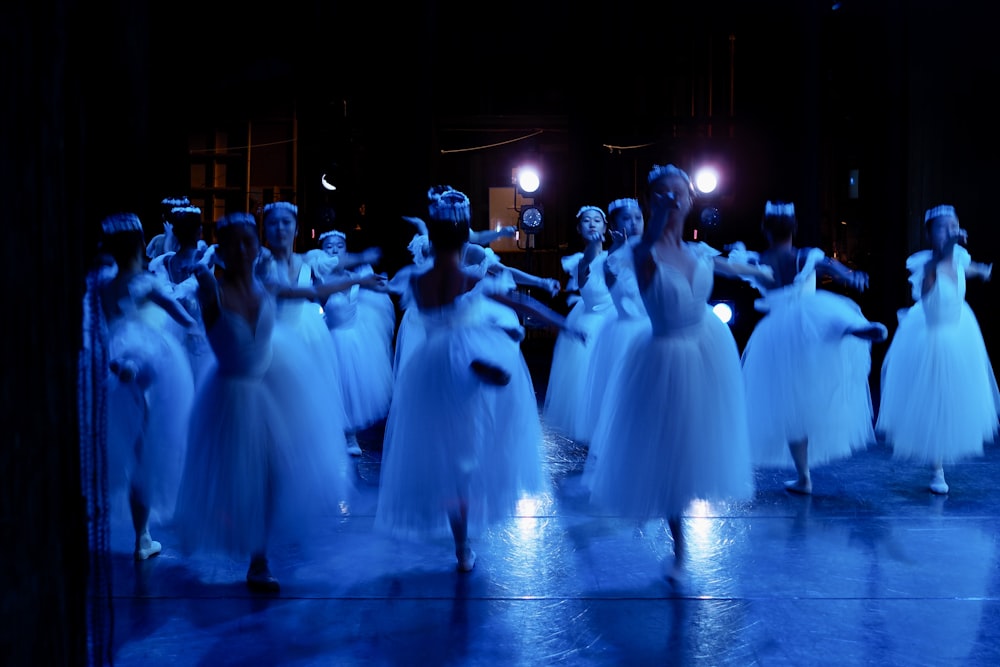 a group of people dressed in white dance on a stage