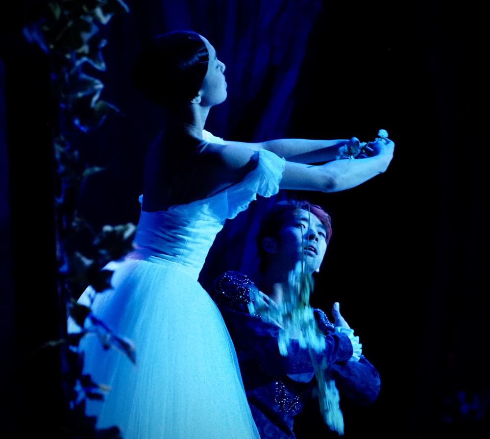 a woman in a white dress standing next to a woman in a blue dress