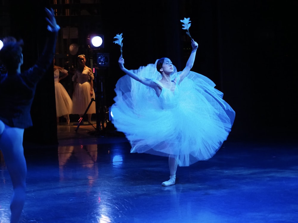 a woman in a white dress is dancing on a stage