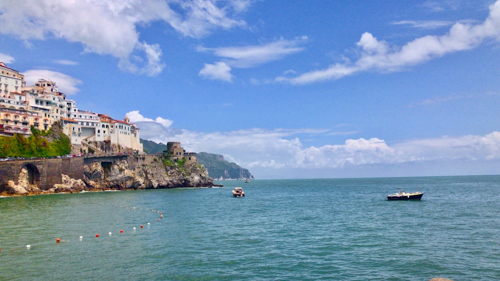 a boat in the water near a city on a cliff