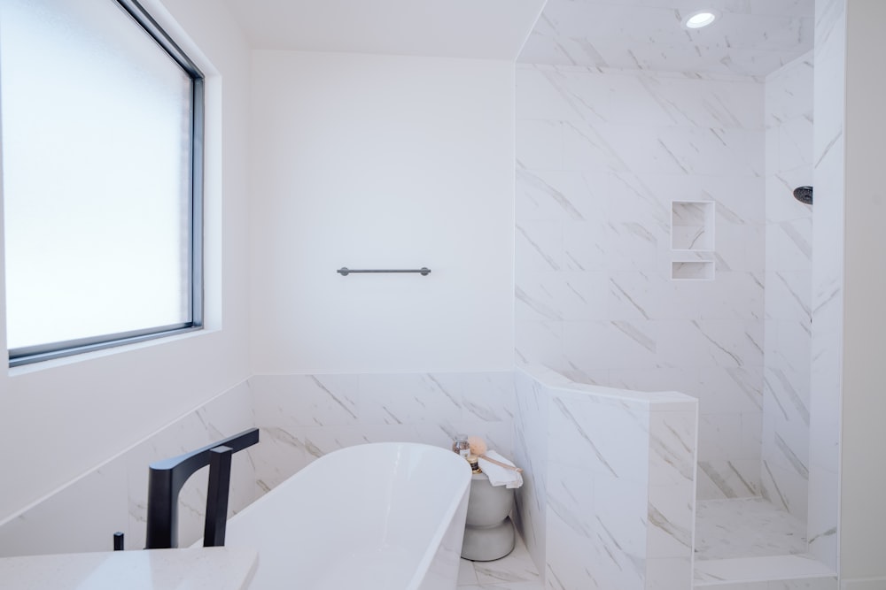 a white bathroom with a tub and a window