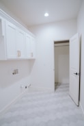 an empty room with white cabinets and a white door