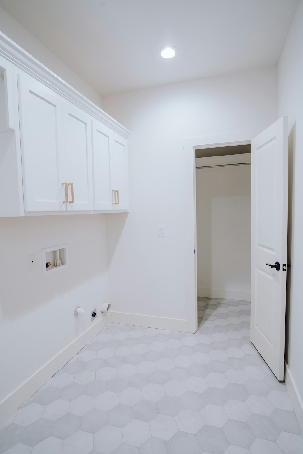 an empty room with white cabinets and a white door