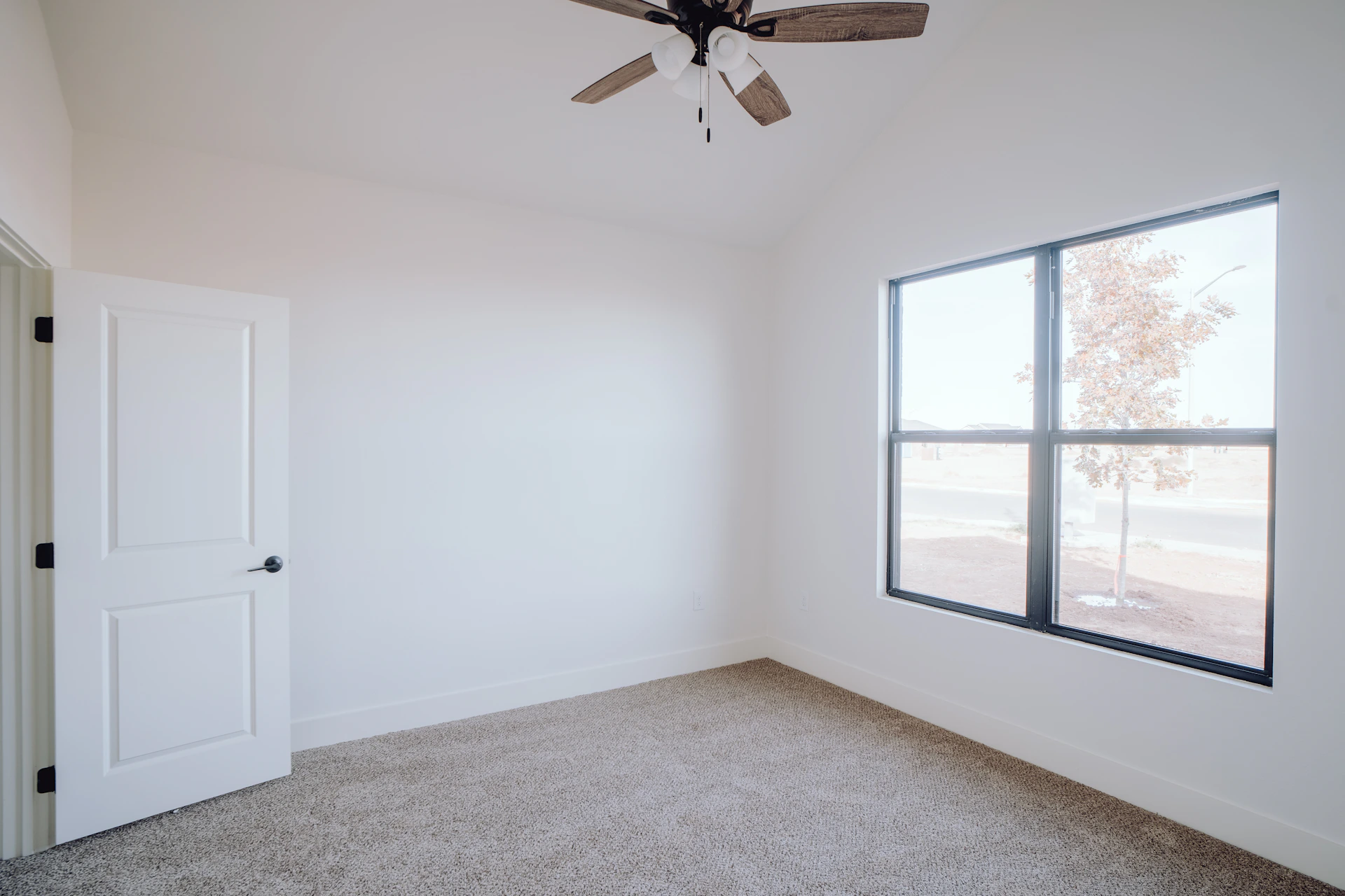an empty room with a ceiling fan and a window