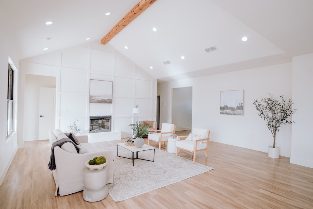 a living room with white furniture and wood floors