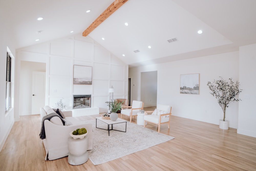 una sala de estar con muebles blancos y suelos de madera