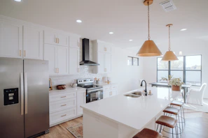 A bright, modern kitchen with white cabinets and a large island, freshly remodeled by Burch Contracting.