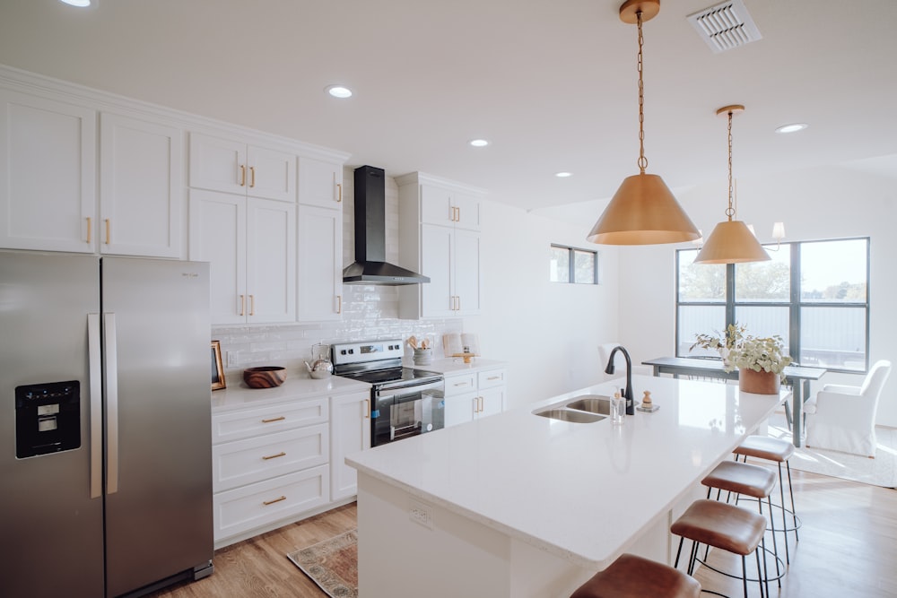 una cocina con gabinetes blancos y un refrigerador plateado