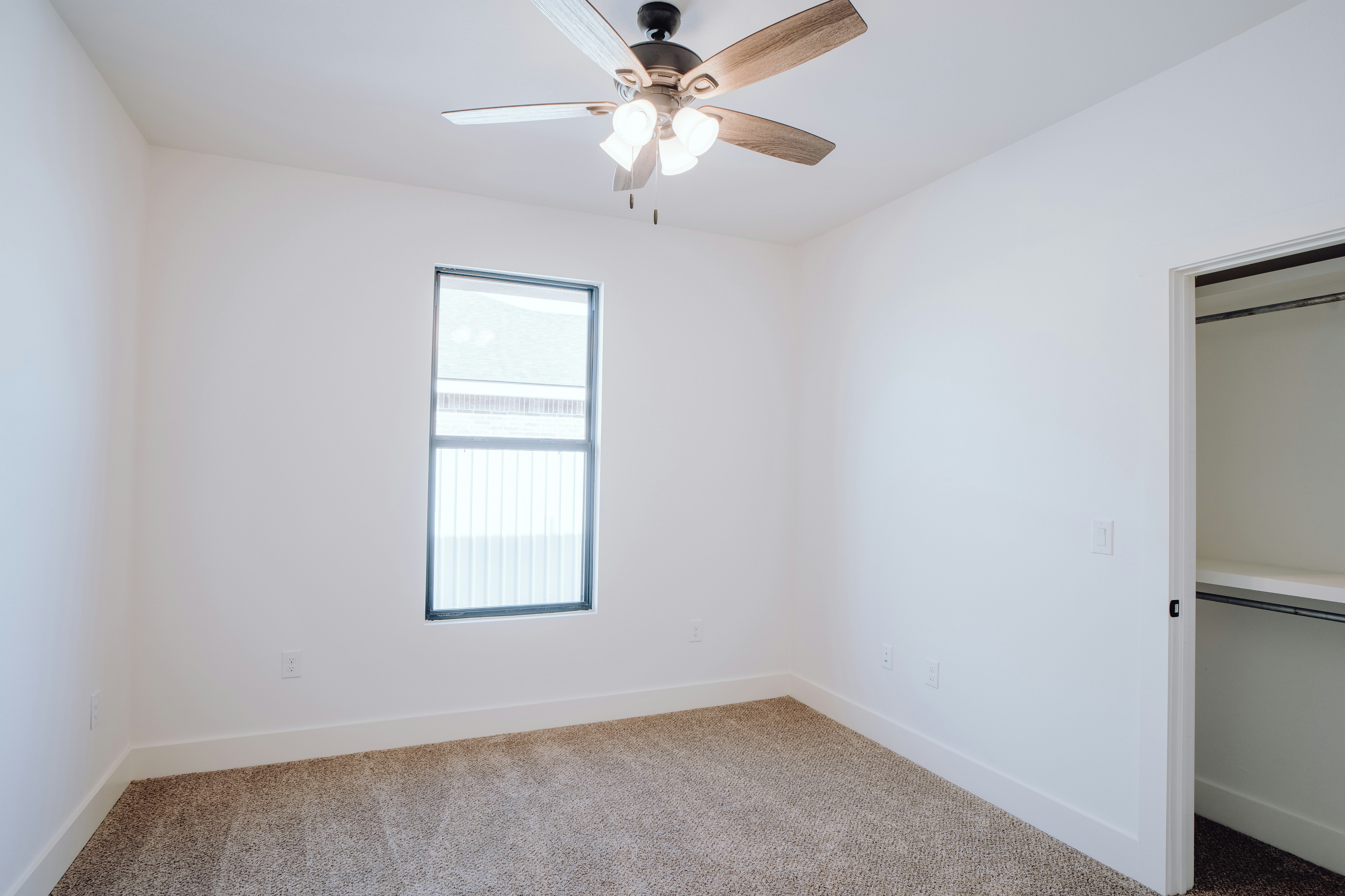 an empty room with a ceiling fan and a window