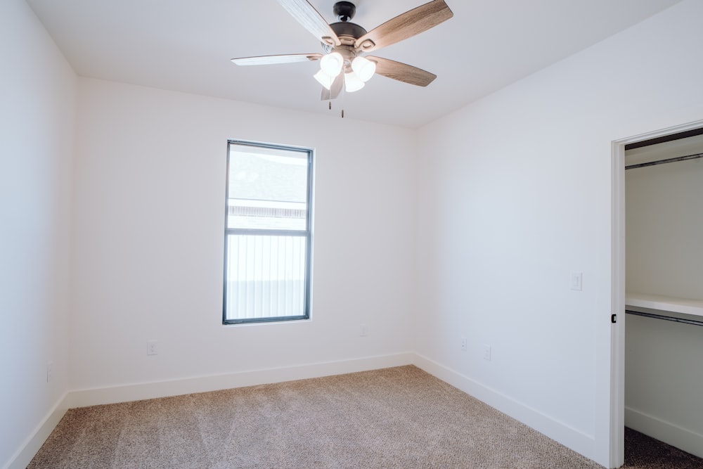 an empty room with a ceiling fan and a window