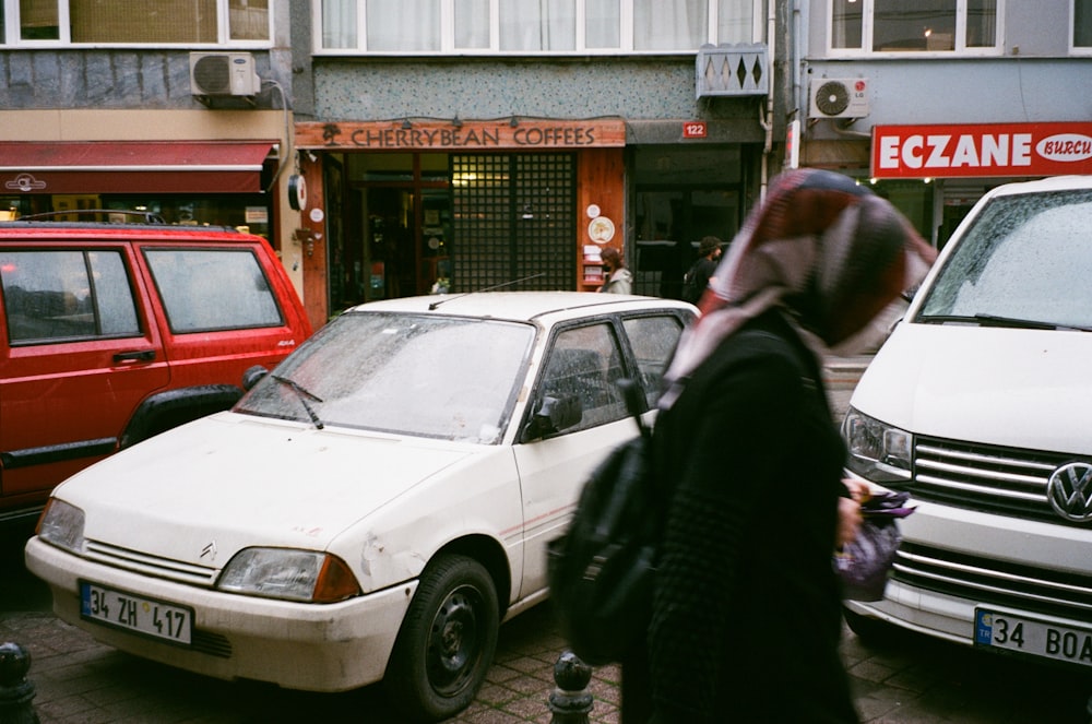 a woman walking down a street next to parked cars