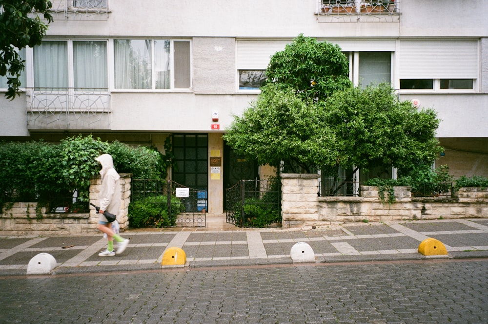 a person walking down a street next to a tall building