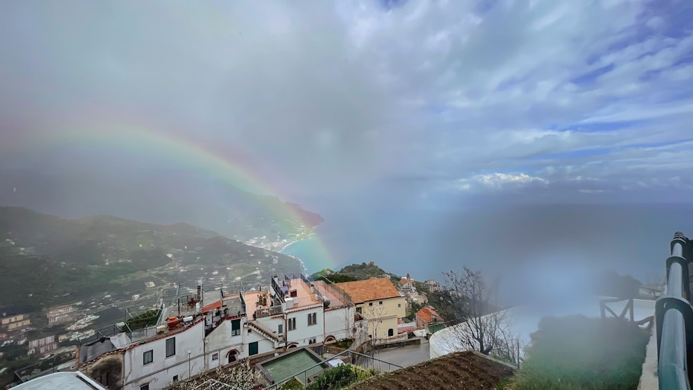 a rainbow appears over a small town on a hill