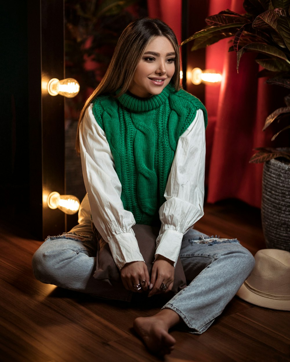 a woman sitting on the floor wearing a green sweater