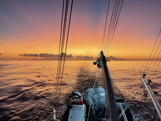 A warm family moment on the deck of the sailboat Paradisean, with the sun setting over calm ocean waters.