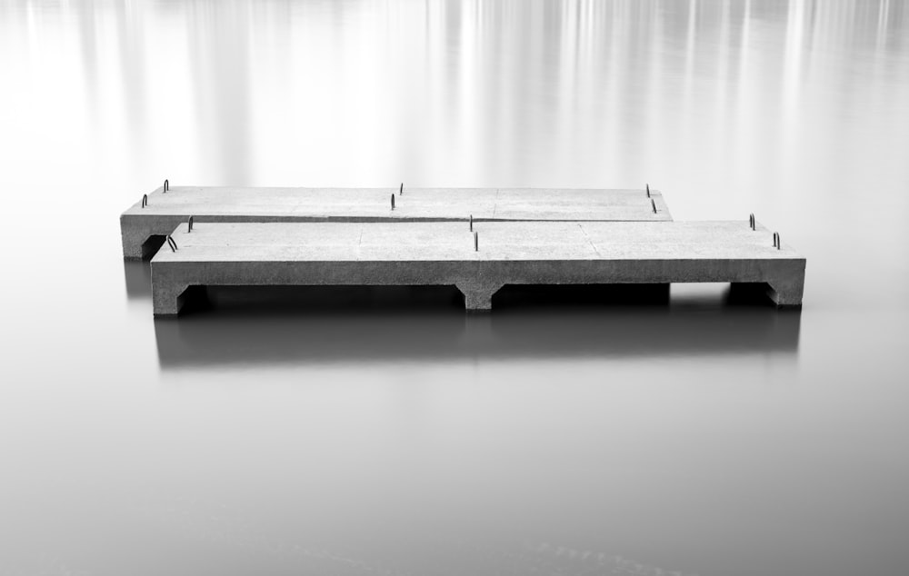 a black and white photo of a bench in water