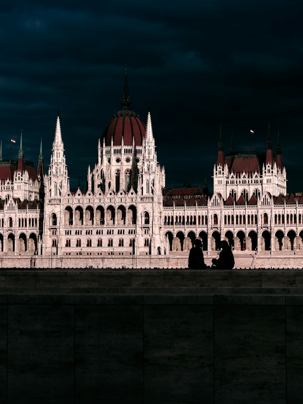 two people sitting on a ledge in front of a building