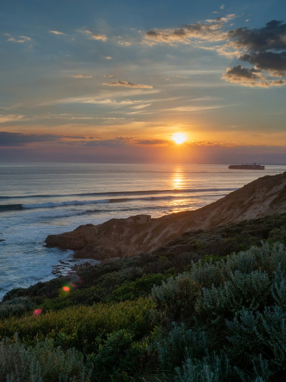 the sun is setting over the ocean and a beach